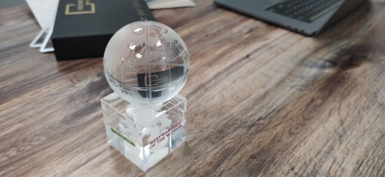 GREENWOOD branded glass on a desk