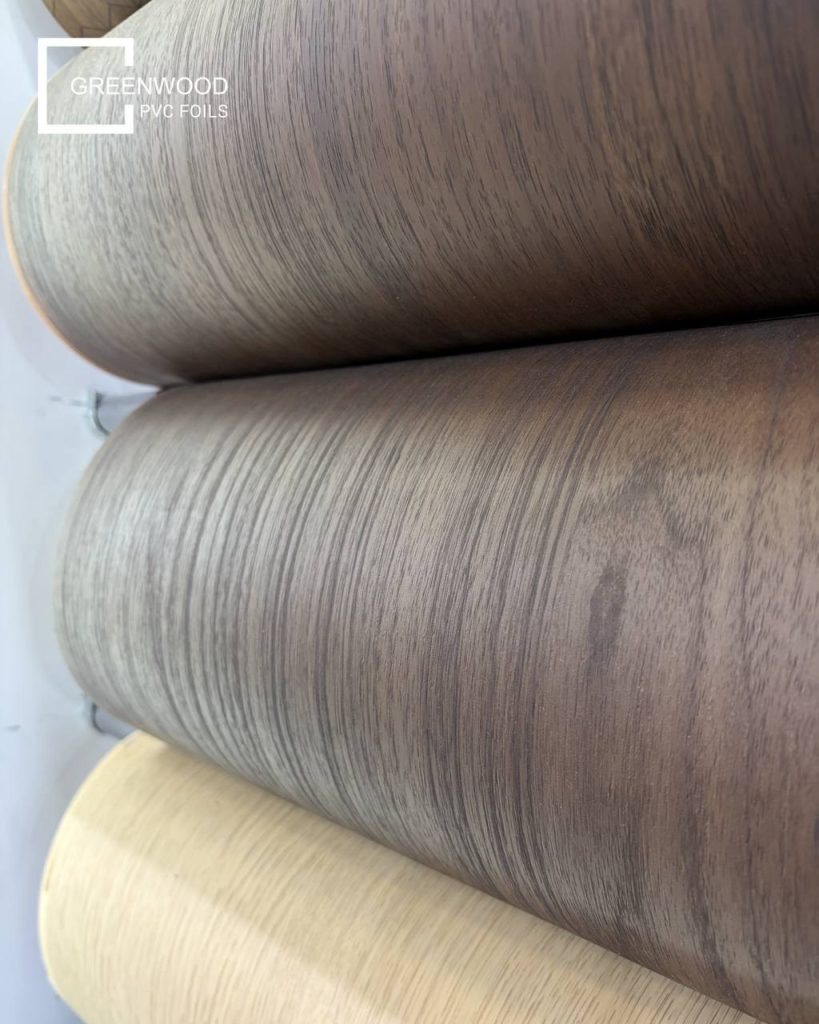 Close-up of decorative PVC film rolls showing woodgrain surface options